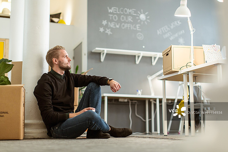 有思想的年轻男性企业家坐在创意办公室的地板上图片素材