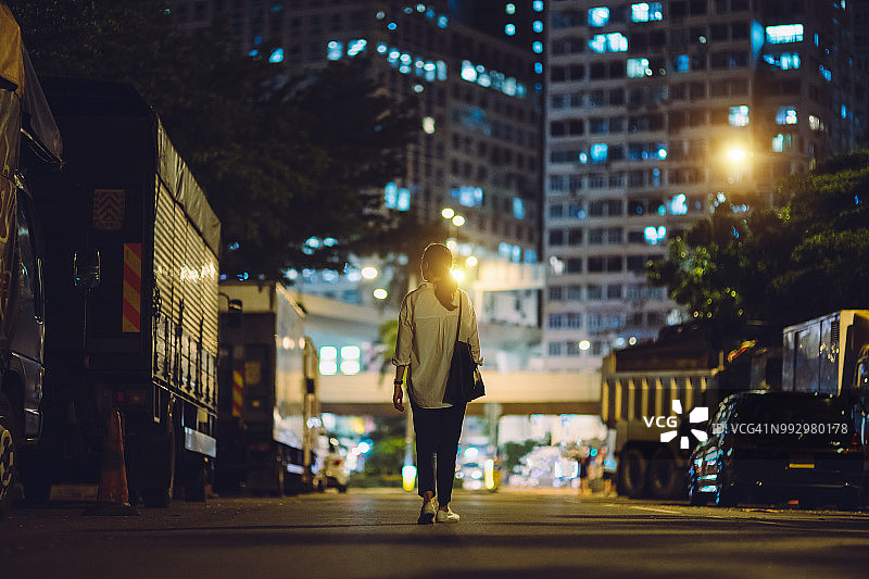 夜晚独自在城市中行走的女人的后视图图片素材
