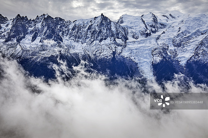 法国阿尔卑斯山脉有雪线。勃朗峰峰顶，山峰和冰川密布，山谷和天空阴云密布图片素材