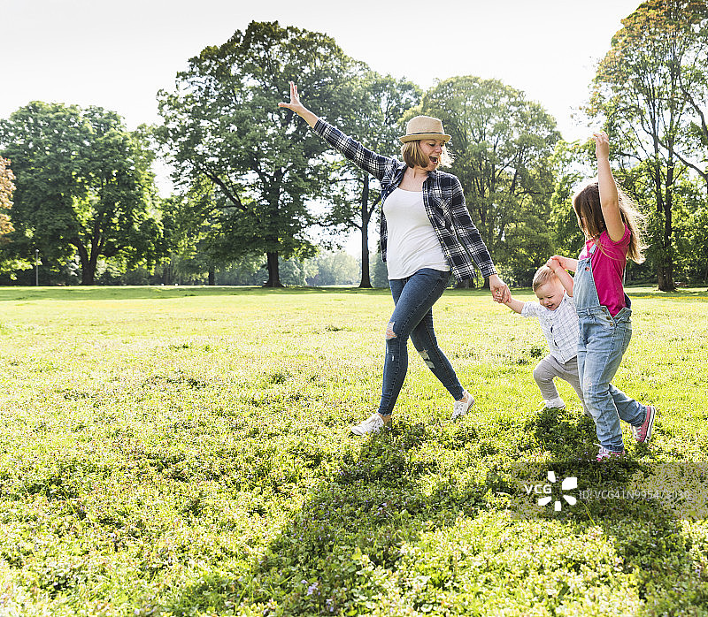 积极快乐的家人手牵手在公园散步图片素材