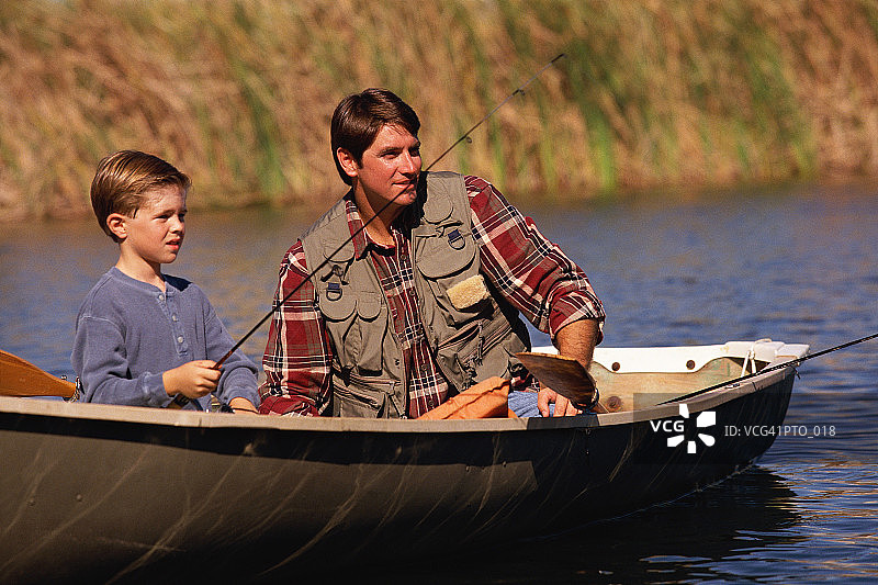 父亲和儿子坐在划艇和钓鱼图片素材