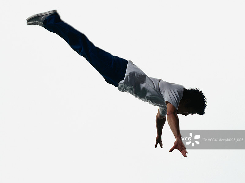 年轻的亚洲人穿着牛仔裤和t恤，在半空中跳图片素材