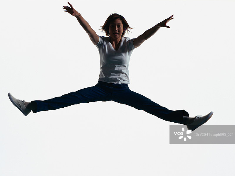 年轻的亚洲女人穿着牛仔裤和t恤，在半空中跳图片素材