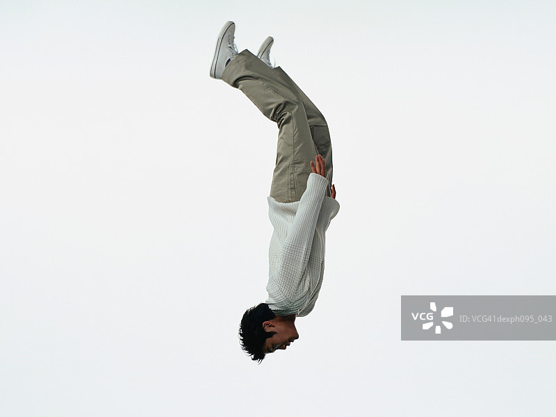 年轻的亚洲人穿着裤子和运动衫，在半空中跳图片素材