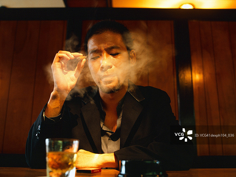 一个男人坐在酒吧里抽烟图片素材