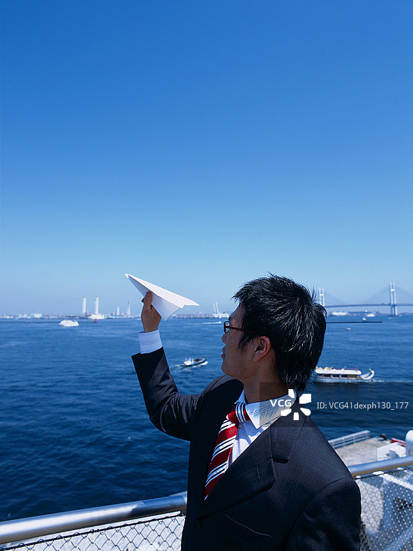 一个年轻人把纸飞机扔到海里图片素材
