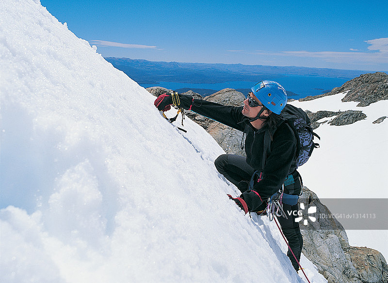 使用岩钉攀登积雪覆盖的岩面的人图片素材
