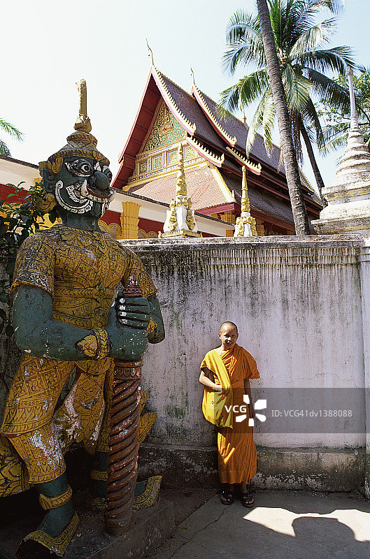 小和尚站在寺庙雕像旁，越南，老挝图片素材