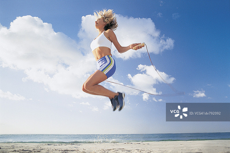 在海滩上跳绳的女人图片素材