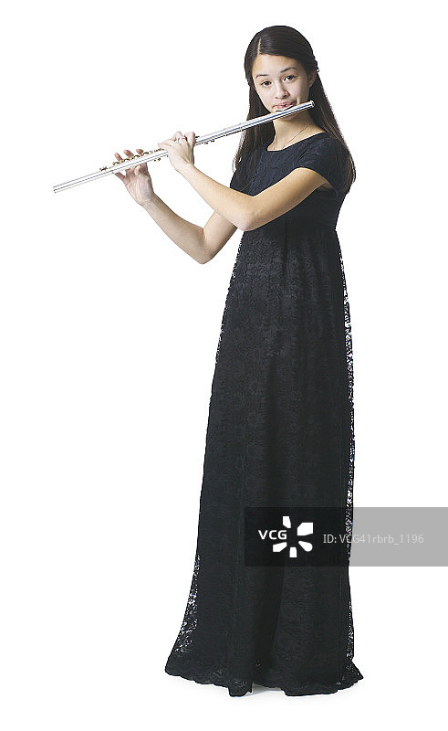 一位穿着黑色长裙的亚洲少女站在那里吹着她的笛子图片素材
