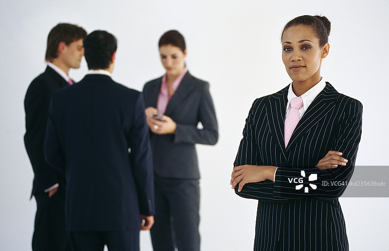 特写女商人站着双臂交叉和三个企业高管在背景图片素材