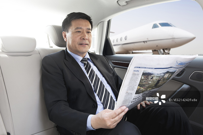 商务男士坐在轿车里看报纸图片素材