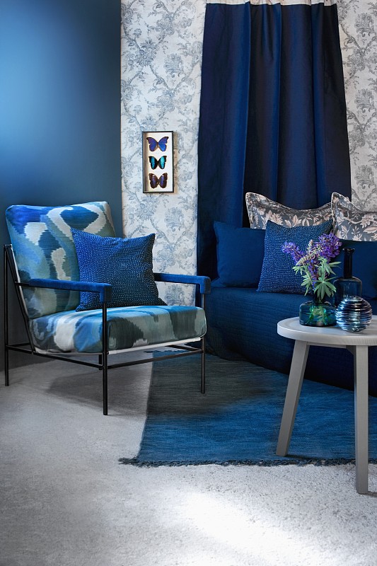 蓝色的座位区有扶手椅、沙发和边桌;在图案墙纸上安装蝴蝶的展示箱图片下载