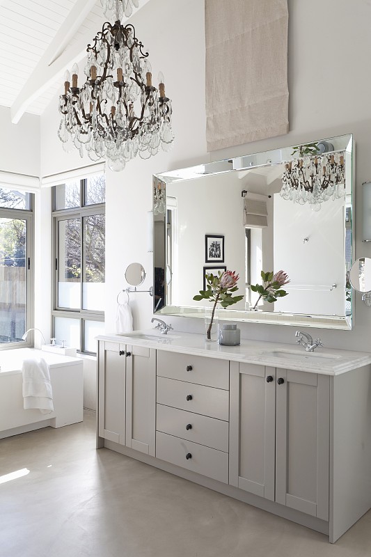 浅灰色浴室盥洗台下优雅的镜子，吊灯和高高的，白色的屋顶结构图片素材
