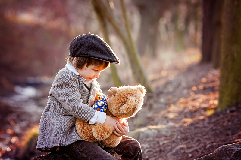 可爱的小男孩和他的泰迪熊朋友在公园里图片下载