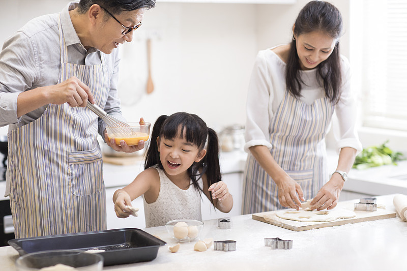 快乐小女孩和爷爷奶奶在厨房制作饼干图片素材