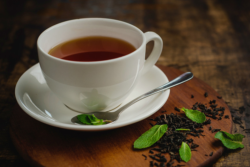 薄荷茶在白瓷杯在一个温暖的木制背景与茶冲泡和薄荷叶饮料图片下载