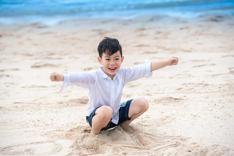 快乐的亚洲男孩在夏天的海滩上玩图片素材