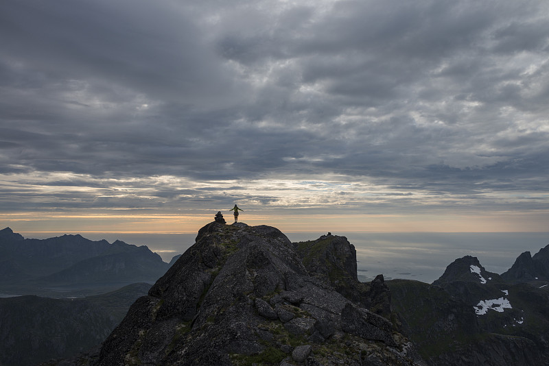 远处的女性徒步者在stjernind山顶日落，Flakstadoya Flakstadoya社区的最高峰Flakstadoya，罗浮敦群岛，挪威图片下载