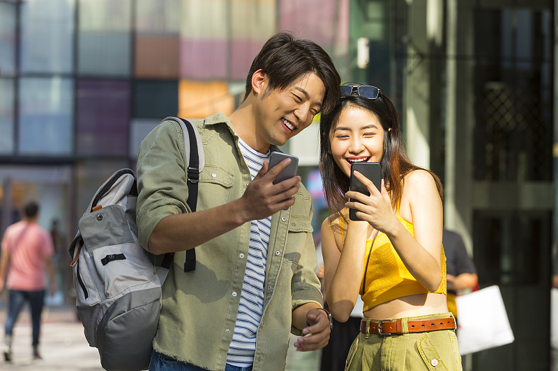 浪漫情侣在户外商业街逛街旅游使用手机图片素材