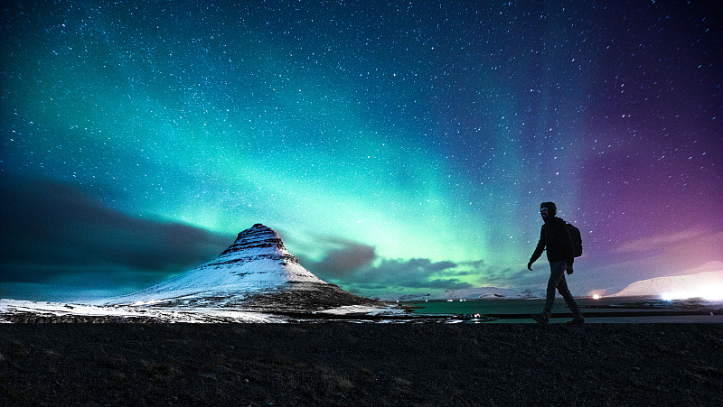 冰岛基尔丘山的北极光落在一名男子的身上图片下载