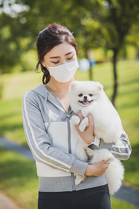 戴着防尘面具，抱着一只狗的女人图片下载