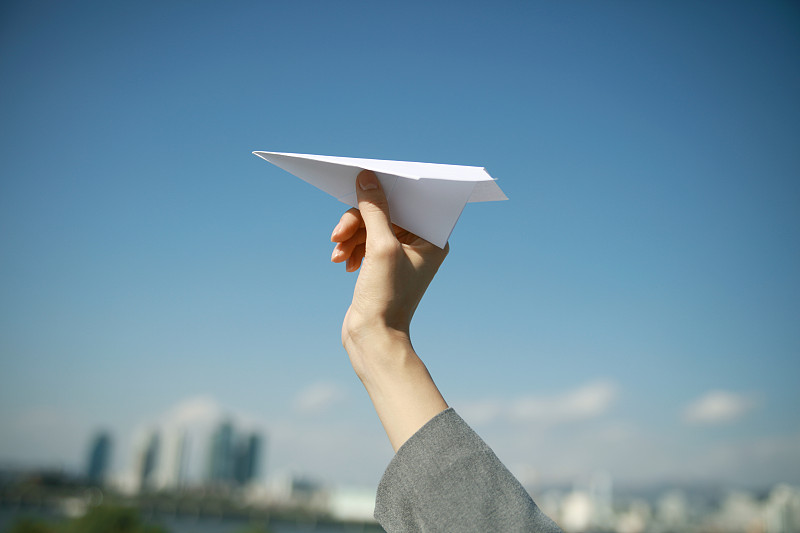 女人拿着纸飞机向着天空的特写图片素材