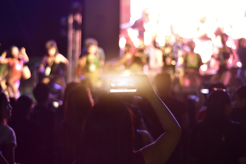 女性在音乐会上使用手机的后视图图片素材