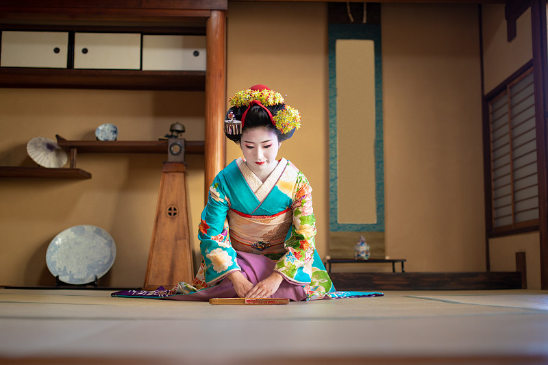 舞子女孩坐在脚跟和鞠躬在传统的日本榻榻米房间图片下载