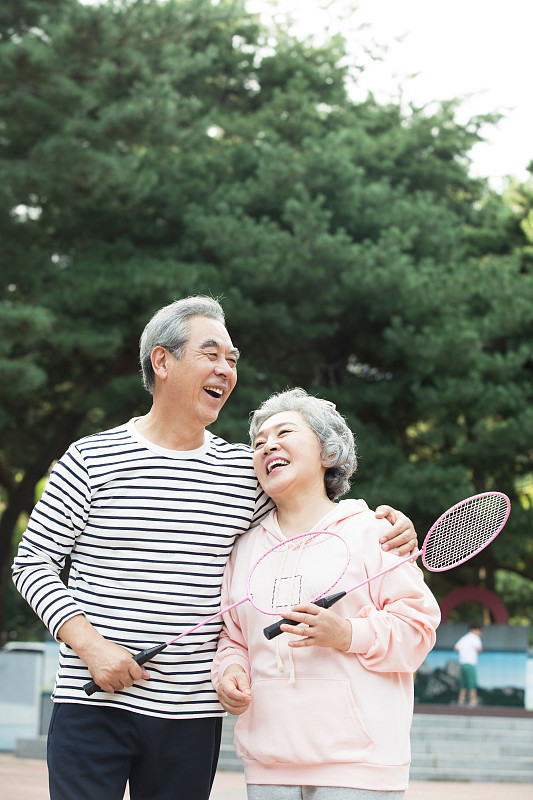 一对老夫妇在公园里笑着打羽毛球图片下载