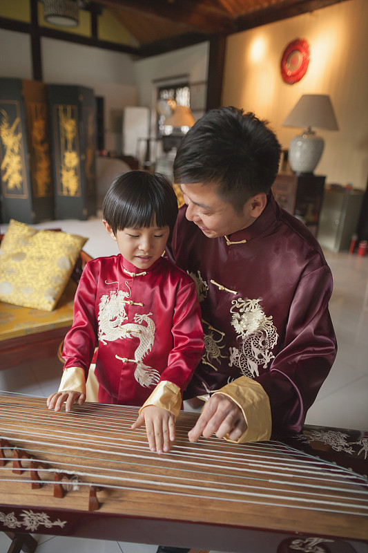 中国的父亲和儿子在传统服装演奏竖琴图片下载