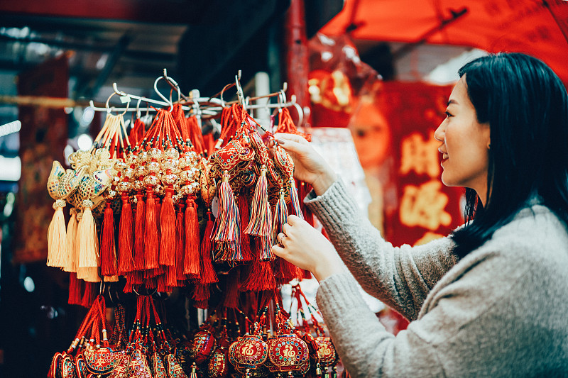 亚洲女性选择色彩鲜艳的中国结装饰中国新年庆祝好运，健康，幸福，团圆和繁荣图片下载