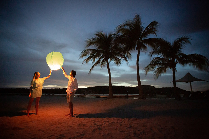 日落时分，一对夫妇在海滩上提着灯笼图片素材