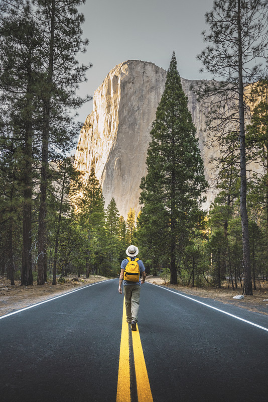 美国加利福尼亚州约塞米蒂国家公园，一名男子走在路上，背景是酋长岩图片下载