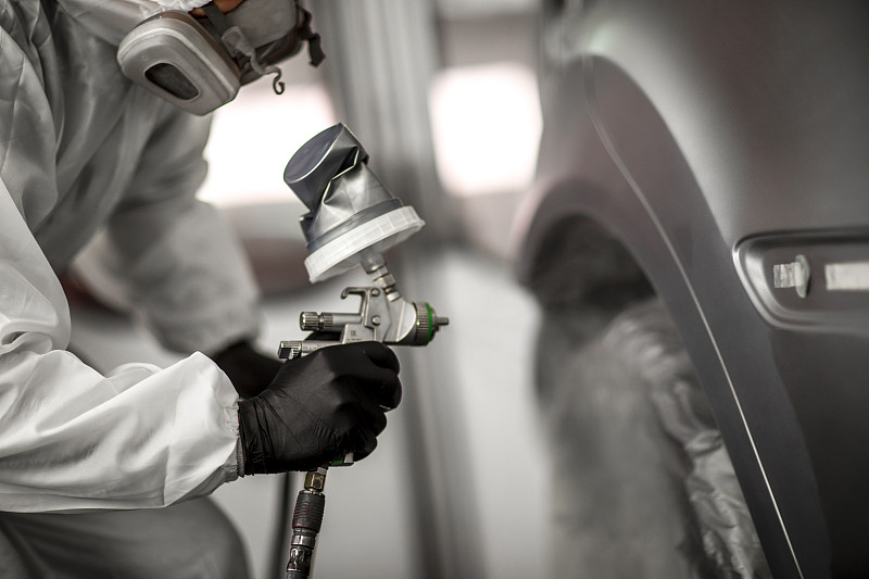 涂装技术员在车身修理厂涂装车间里，在汽车上涂抹一层涂料图片素材