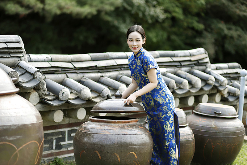 穿着旗袍的女子站在长穴台，韩国传统的坛子旁图片素材