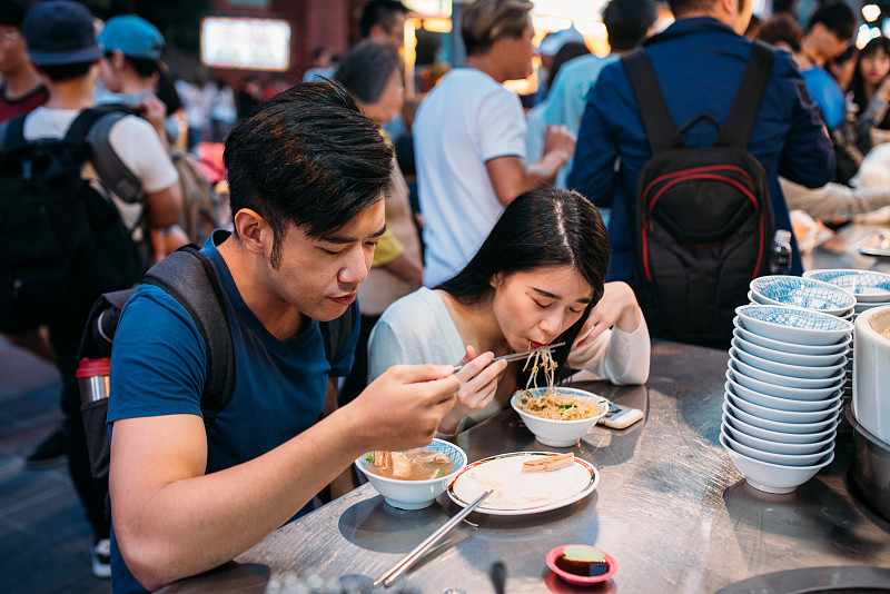 可爱的年轻亚洲夫妇在台北夜市享受街头小吃。图片素材