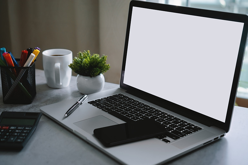 笔记本电脑与空白白屏幕和办公用品的文书桌上图片素材
