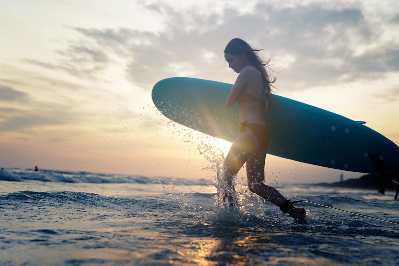 美丽的亚洲女子冲浪者在比基尼享受夏天的海滩冲浪板。图片下载