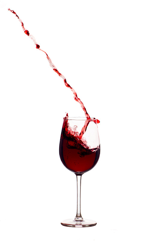 在白色背景下，红酒在玻璃杯中飞溅图片素材