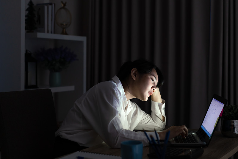 年轻的亚洲单身女学生工作到深夜压力与项目研究问题在电脑上或笔记本电脑在家里办公室。亚洲人职业倦怠综合症的概念。图片素材