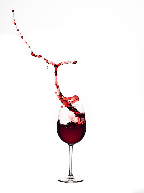 在白色背景下，红酒在玻璃杯中飞溅图片下载