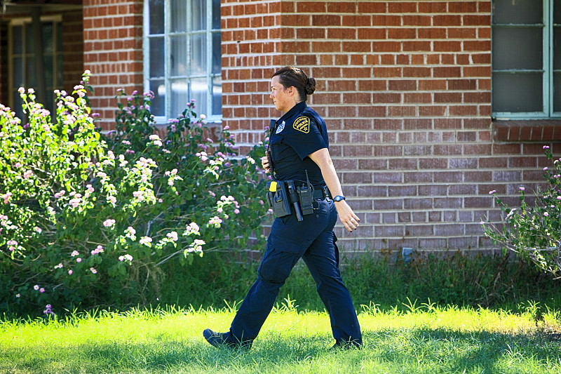 图森市，一名警察在紧张时刻穿过一户人家的前院图片下载