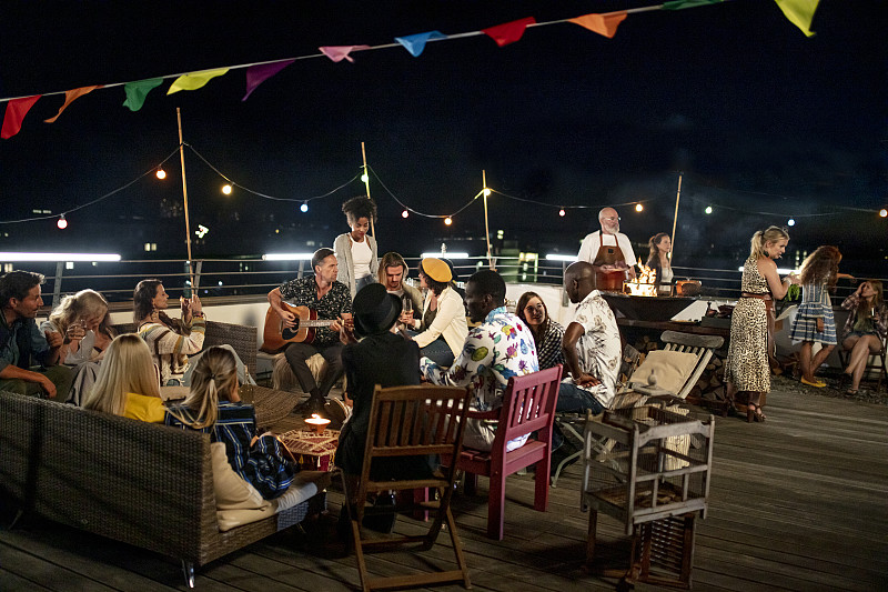 一大群朋友坐在一起享受夏季城市屋顶派对在慕尼黑图片素材