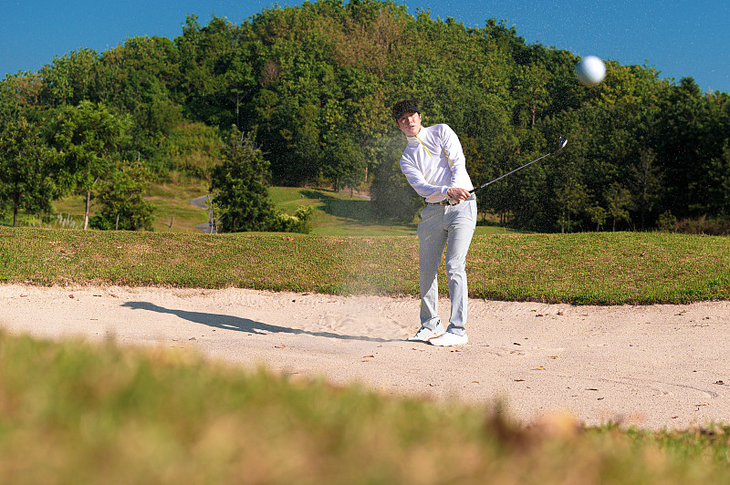 高尔夫球手在沙坑中挥杆图片下载