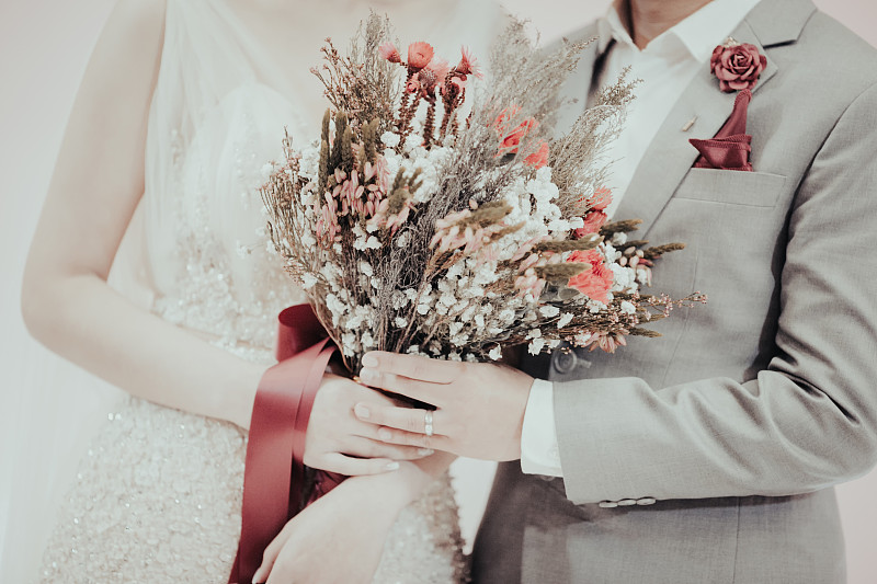 新娘和新郎手中捧着一束鲜花。图片下载