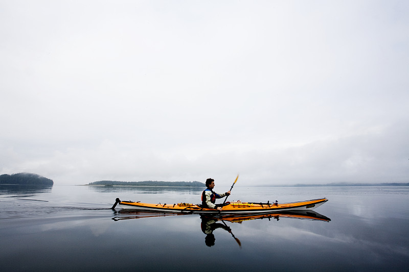 男子皮划艇在阴天平静的水图片下载