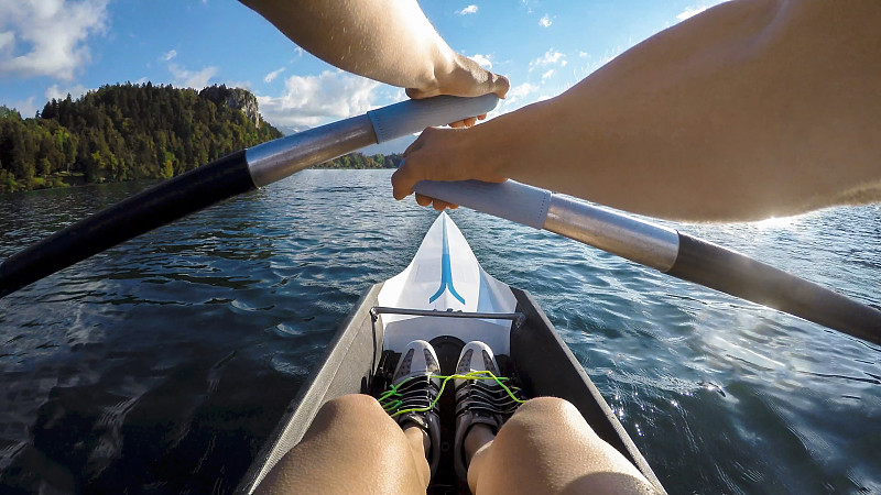运动员在阳光明媚的湖面上划桨图片下载