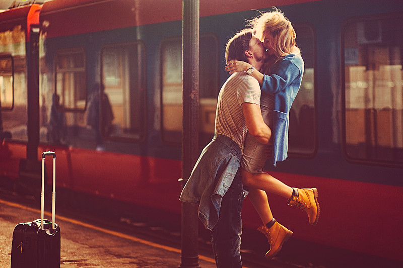 热情洋溢的青年男女在火车站的火车旁边热吻图片素材