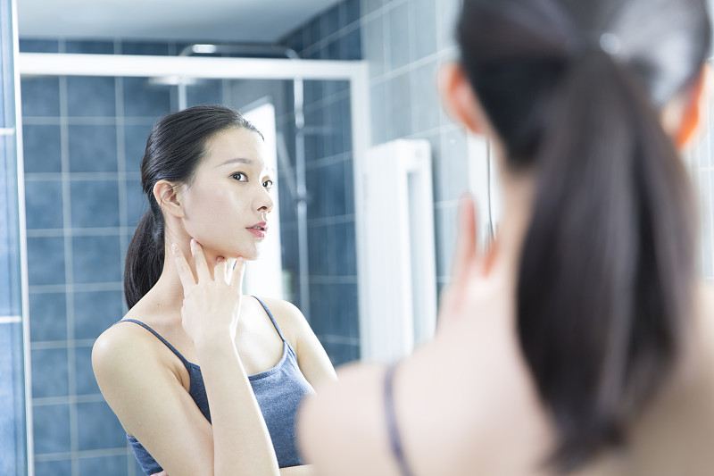 青年女子在卫生间照镜子美容护肤图片素材